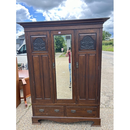 66 - A large carved oak three door wardrobe on two drawer base 155x50x205