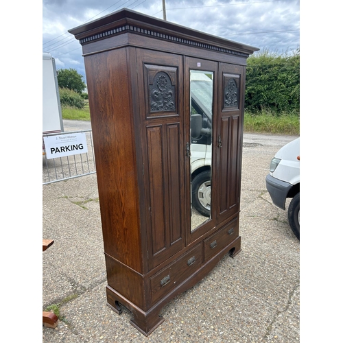 66 - A large carved oak three door wardrobe on two drawer base 155x50x205