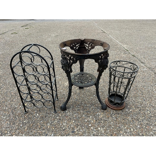 83 - An iron Britannia style table base together with a metal wine rack and umbrella stand