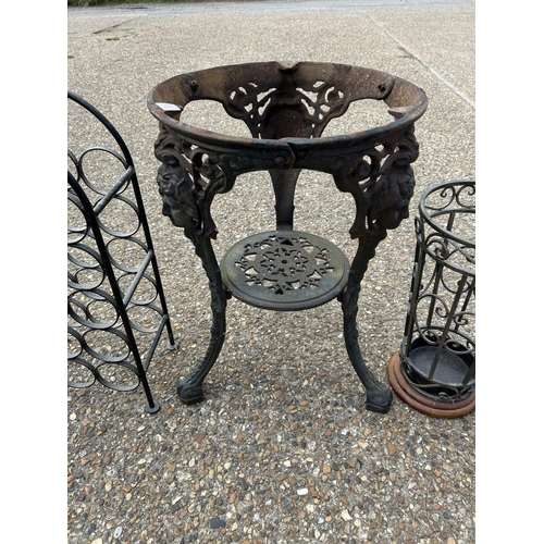 83 - An iron Britannia style table base together with a metal wine rack and umbrella stand