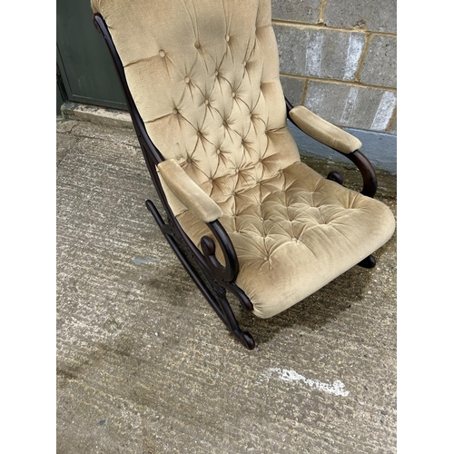 38 - A carved mahogany framed rocking chair with gold buttoned upholstery