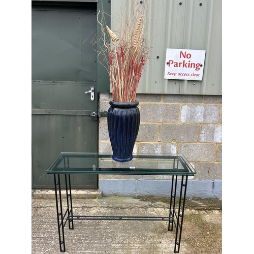 44 - A modern glass topped hall table together with a glazed pot containing sticks