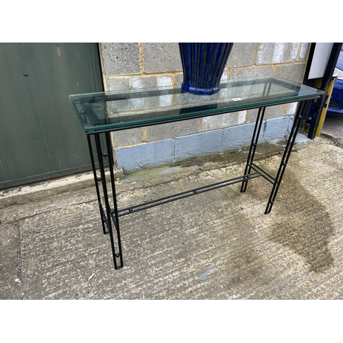 44 - A modern glass topped hall table together with a glazed pot containing sticks