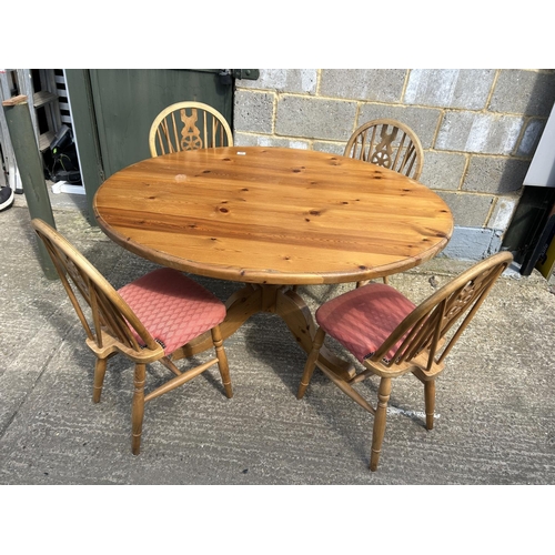 94 - An oval pine kitchen table together with four wheelback chairs