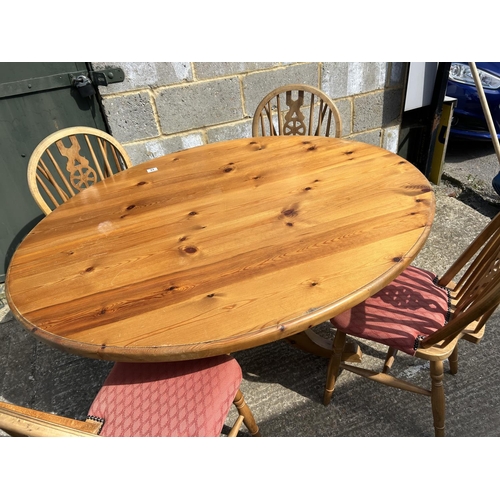 94 - An oval pine kitchen table together with four wheelback chairs