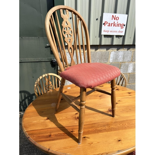 94 - An oval pine kitchen table together with four wheelback chairs