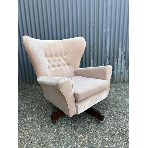 194 - A mid century pink upholstered swivel and recline wing back armchair