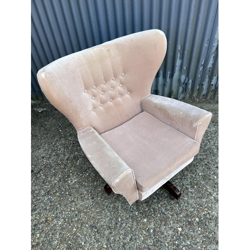 194 - A mid century pink upholstered swivel and recline wing back armchair