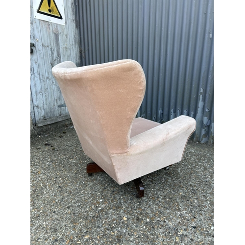 194 - A mid century pink upholstered swivel and recline wing back armchair