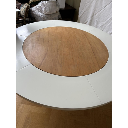 76 - A mid century circular dining table with 'trip trap' stlye extension leaves