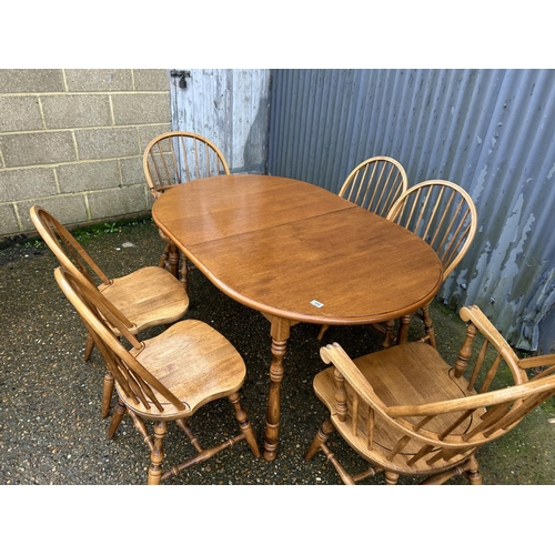 169 - An extending oak dining table together with a set of stick back chairs