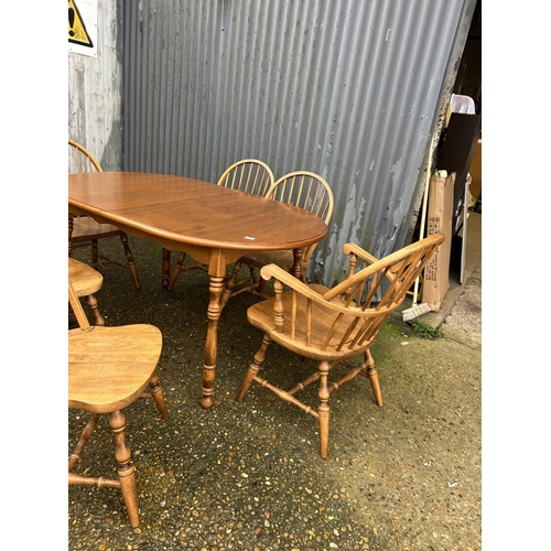 169 - An extending oak dining table together with a set of stick back chairs