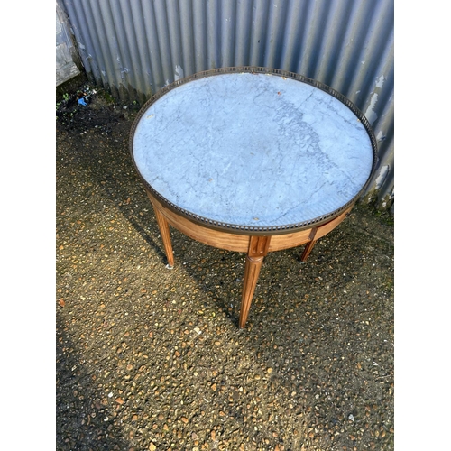 215 - A continental circular mahogany table with a white marble top and brass gallery. Fitted with two dra... 