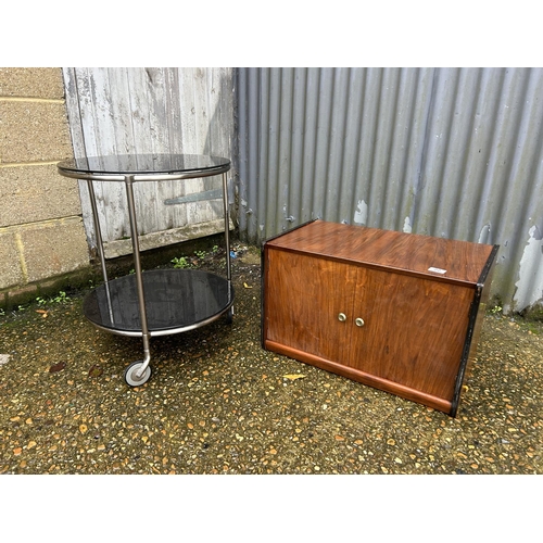 22 - A two door record cupboard together with a retro chrome circular trolley with black glass top