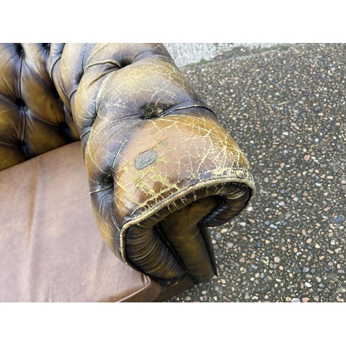 63 - A golden brown leather chesterfield three seater sofa