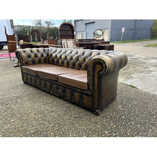 63 - A golden brown leather chesterfield three seater sofa