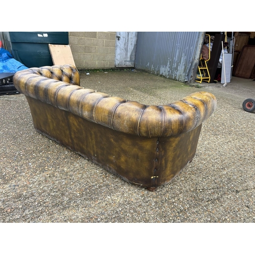 63 - A golden brown leather chesterfield three seater sofa