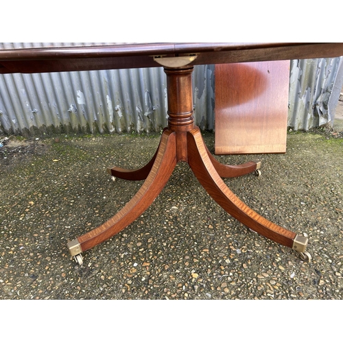 67 - A reproduction mahogany single pedestal dining table with extension leaf 138x106