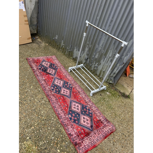 100 - A thin red oriental runner together with modern clothes rail