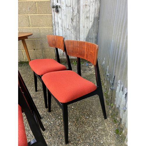 138 - A teak drop leaf dining table together with a set of four teak chairs with orange upholstered seats