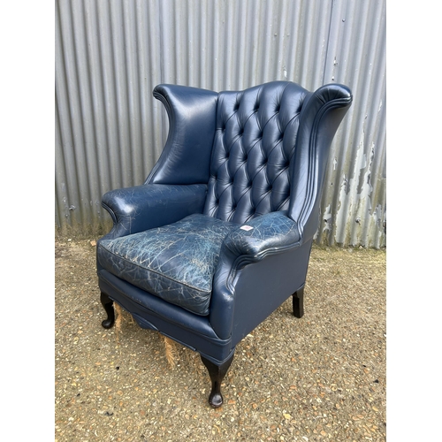 183 - A blue leather chesterfield wing back armchair