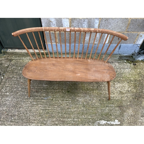 248 - An ercol light elm stick back bench seat