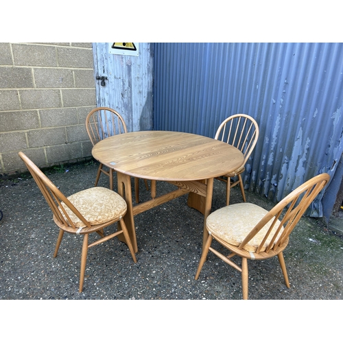 31 - A ercol light elm gate leg table with four stick back chairs