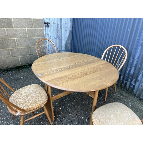 31 - A ercol light elm gate leg table with four stick back chairs