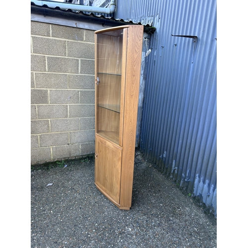 32 - An ercol light elm corner cabinet with glazed door and illuminating interior