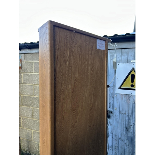 32 - An ercol light elm corner cabinet with glazed door and illuminating interior