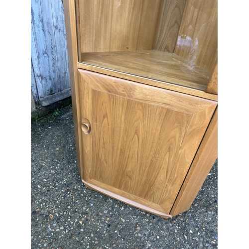 32 - An ercol light elm corner cabinet with glazed door and illuminating interior