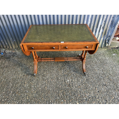 52 - A reproduction yew wood writing table with drop leaf ends and a green leather top