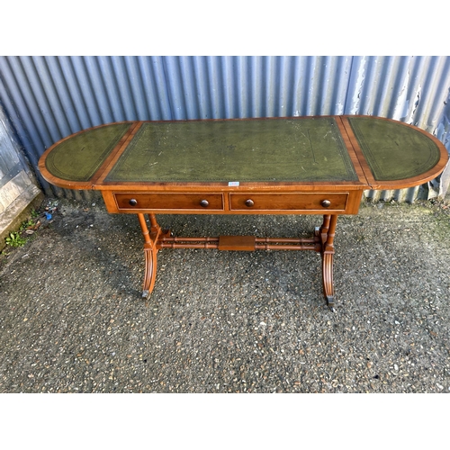 52 - A reproduction yew wood writing table with drop leaf ends and a green leather top