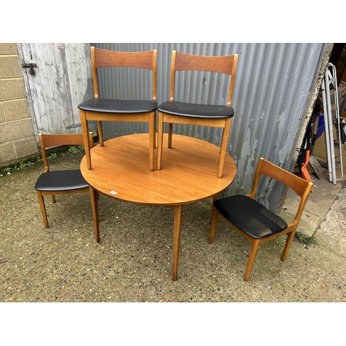 218 - A mid century circular teak extending dining table together with four teak dining chairs with black ... 