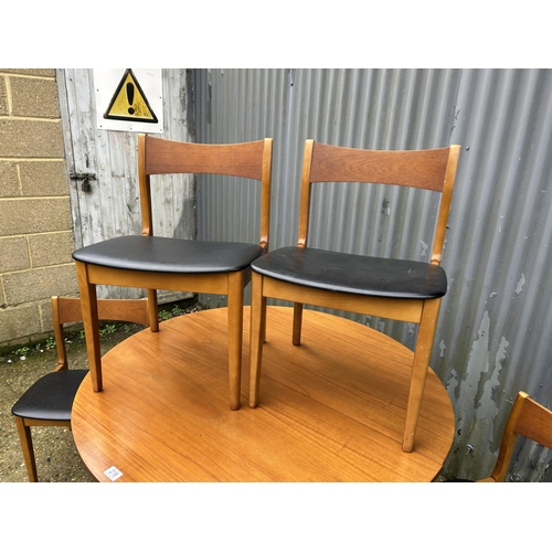 218 - A mid century circular teak extending dining table together with four teak dining chairs with black ... 