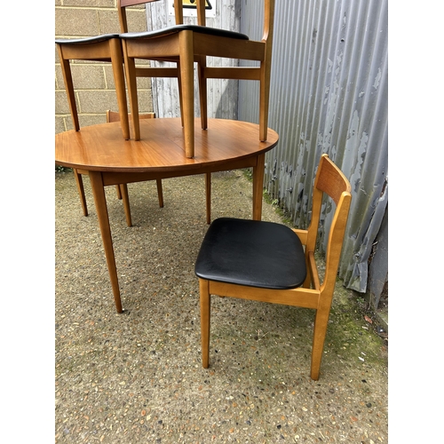 218 - A mid century circular teak extending dining table together with four teak dining chairs with black ... 