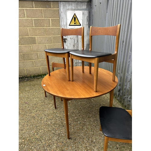 218 - A mid century circular teak extending dining table together with four teak dining chairs with black ... 