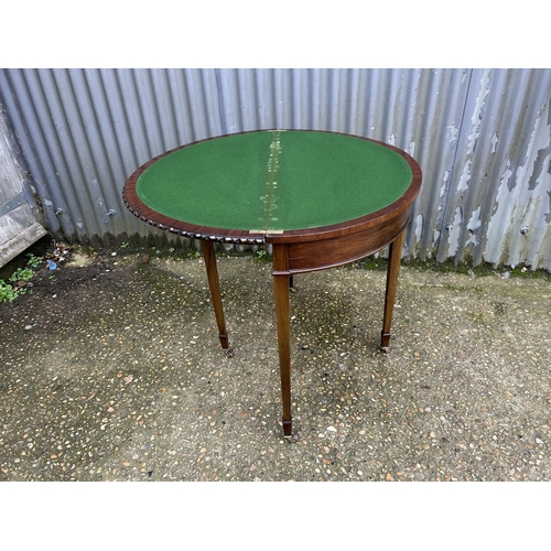 36 - A mahogany demi lune card table with green baize