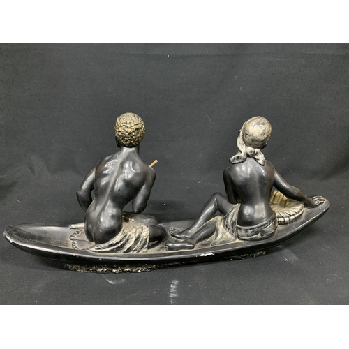 557 - Ethnic plaster ornament of two figures paddling boat, length 67cms, height 30cms