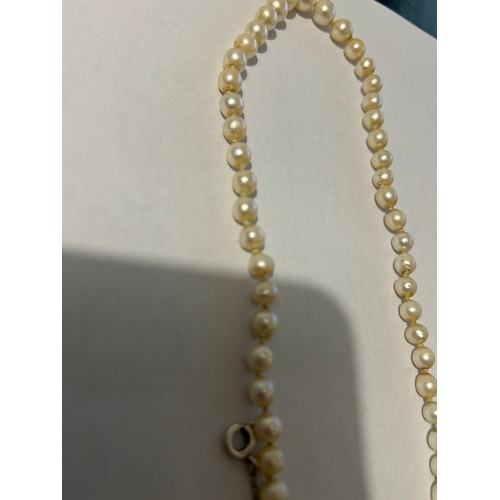 894 - A single strand of graduating pearls, individually knotted (untested) with a later added safety chai... 