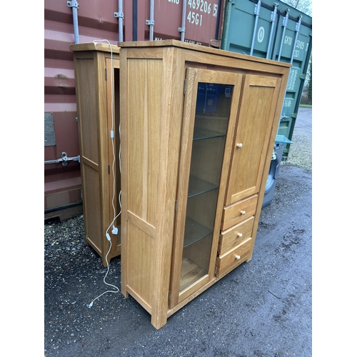 25 - A glazed light oak bookcase cabinet with three drawers 106x40x155