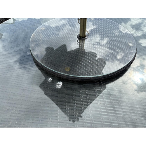 481 - A  modern black ratan garden table together with six chairs,  lazy Susan and parasol 142cm diameter