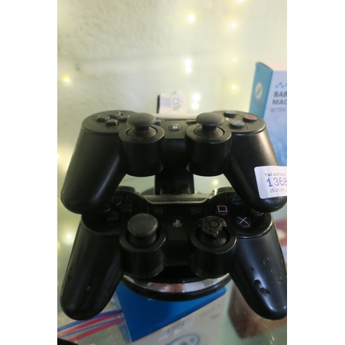 1368 - 2 SONY CONTROLLERS ON CHARGING STAND (NO CHARGING CABLE)