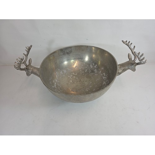 19 - A large decorative polished metal champagne cooler with stag head handles. 23cm h x 40cm d x 64cm w... 