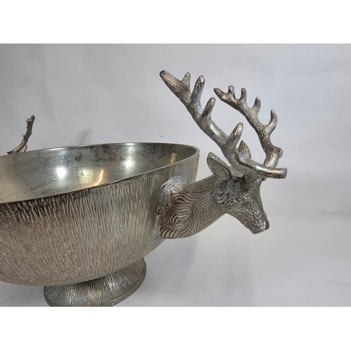19 - A large decorative polished metal champagne cooler with stag head handles. 23cm h x 40cm d x 64cm w... 
