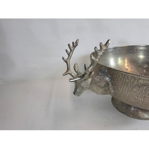 19 - A large decorative polished metal champagne cooler with stag head handles. 23cm h x 40cm d x 64cm w... 
