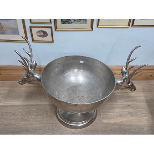 21 - A very large antique style polished metal 24 bottle champagne cooler in the form of a footed bowl, w... 
