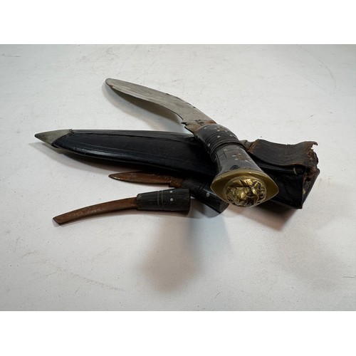 41 - A 20thC Indian Kukri, a principal knife, with a lion's head terminal, two smaller knives, in a toole... 