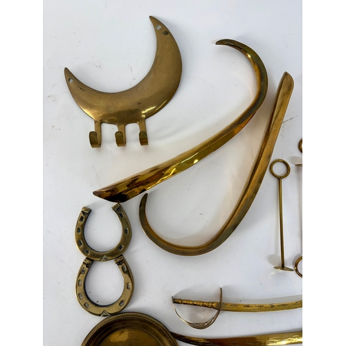 85 - A selection of early 20th century brass ornaments and collectibles to include button polisher slides... 