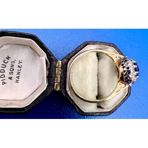 115 - A Sapphire and diamond cluster dress ring on 18ct white and yellow gold.The oval cut sapphire aprox ... 